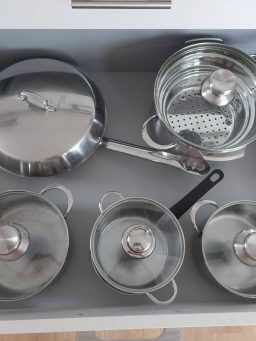 Küchenschublade mit verschiedenen Töpfen und Pfannen aus Edelstahl.
